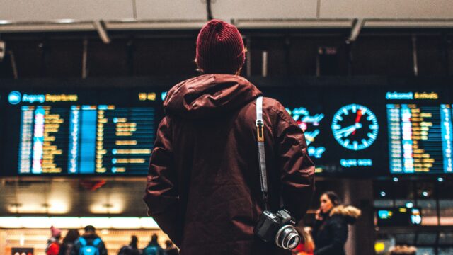 Ragazzo guarda il tabellone con gli orari alla stazione di Oslo in Norvegia